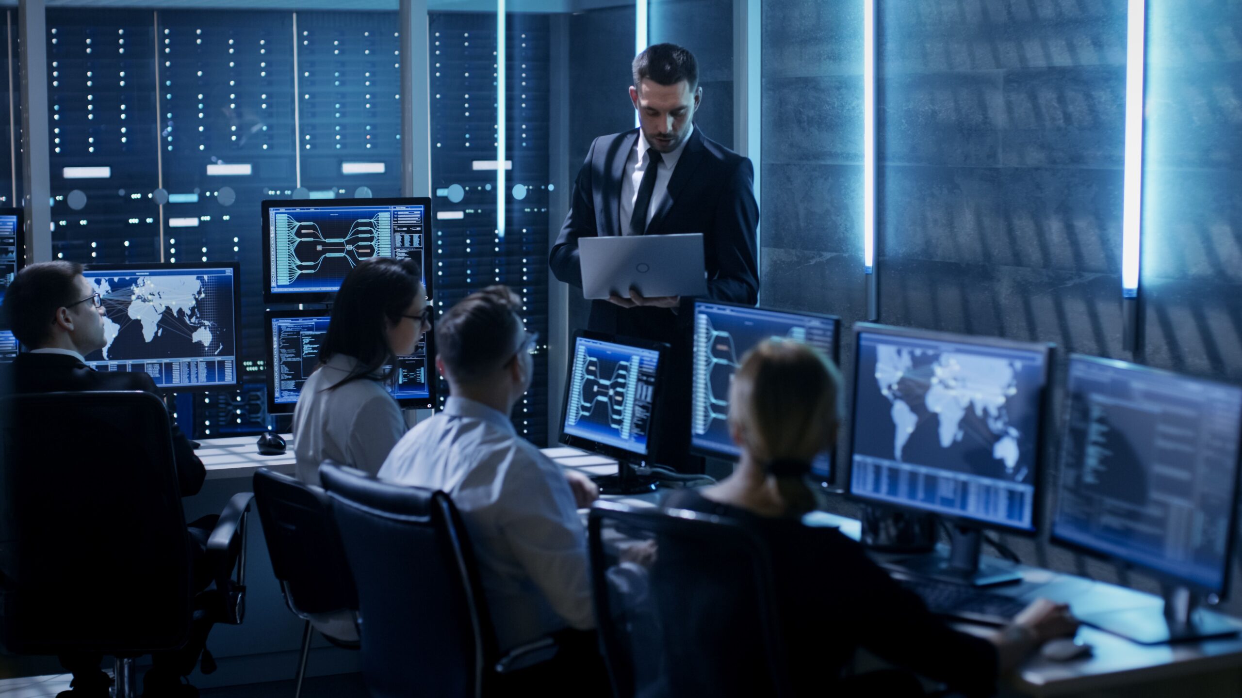 A man wearing glasses is focused on his work at a computer, typing and analyzing information on the screen